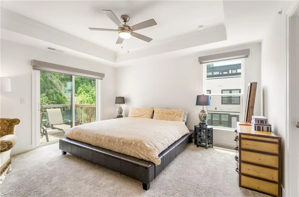 Bedroom with access to exterior, carpet, a tray ceiling, and a ceiling fan