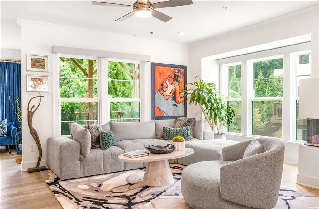 Living room featuring light wood-style floors, plenty of natural light, ornamental molding, and ceiling fan