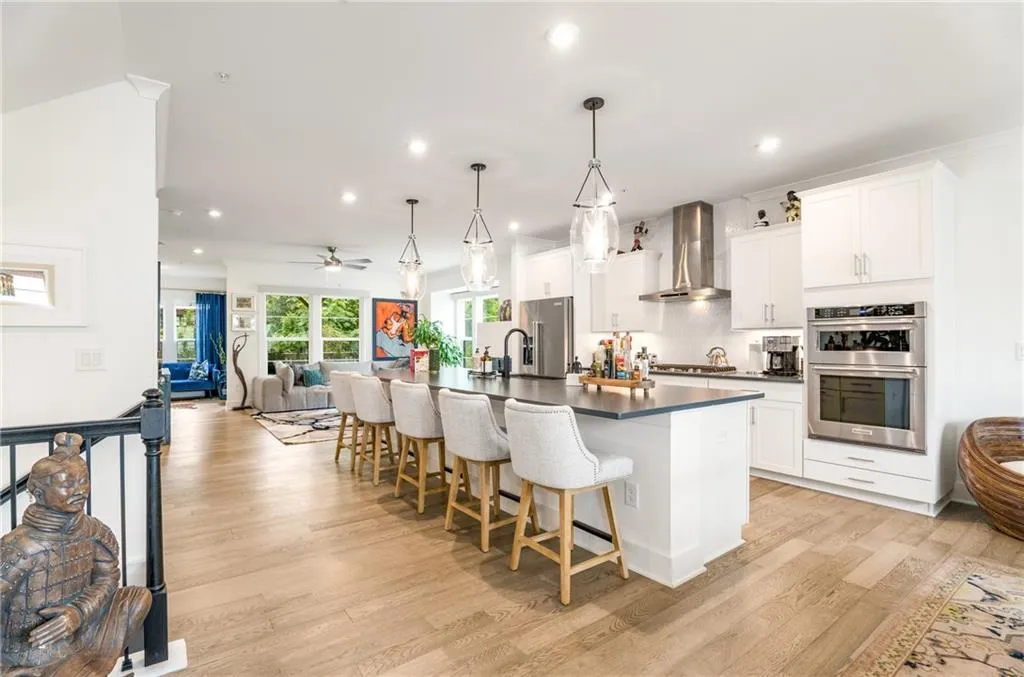 Kitchen with open floor plan, dark countertops, wall chimney exhaust hood, decorative backsplash, and a breakfast bar area