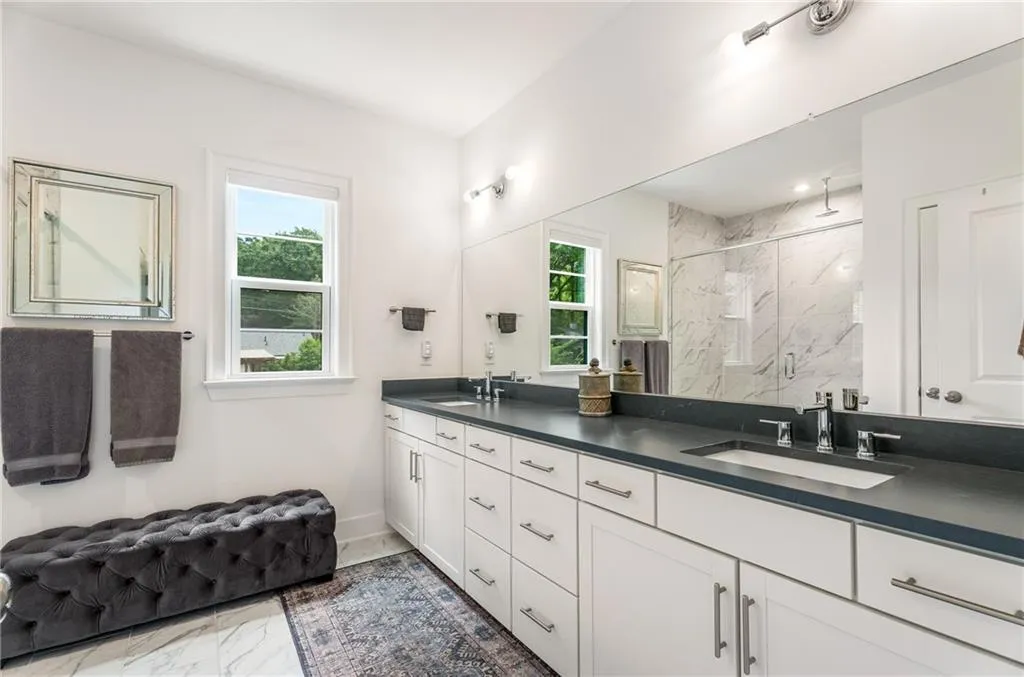 Bathroom with marble finish floors, double vanity, a marble finish shower, and plenty of natural light