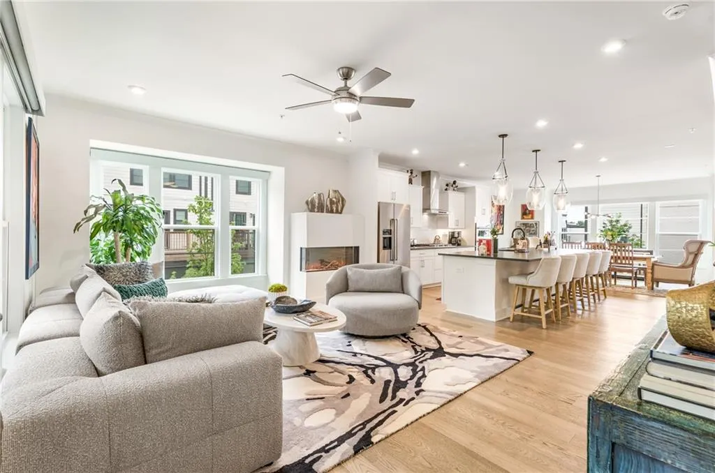 Living area featuring light wood-style flooring, ceiling fan, recessed lighting, a warm lit fireplace, and ornamental molding