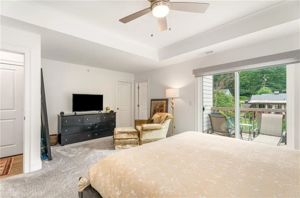 Carpeted bedroom featuring access to outside, ceiling fan, and a raised ceiling
