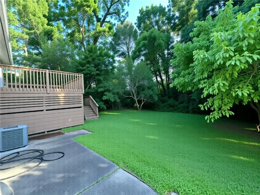 View of grassy yard with a deck and a patio