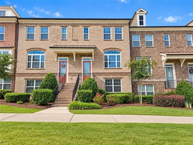Brick exterior with multiple windows, architectural dormer, and covered entryways