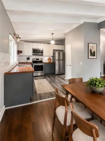 Kitchen featuring stainless steel appliances, white upper cabinetry, gray lower cabinetry, and wood-finish countertops