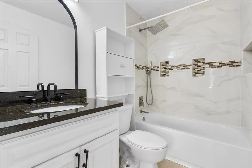 Bathroom featuring  shower combination, toilet, and vanity