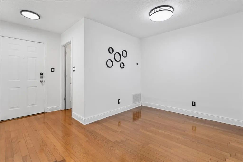 Foyer entrance with light wood-style floors, baseboards, visible vents, and a textured ceiling