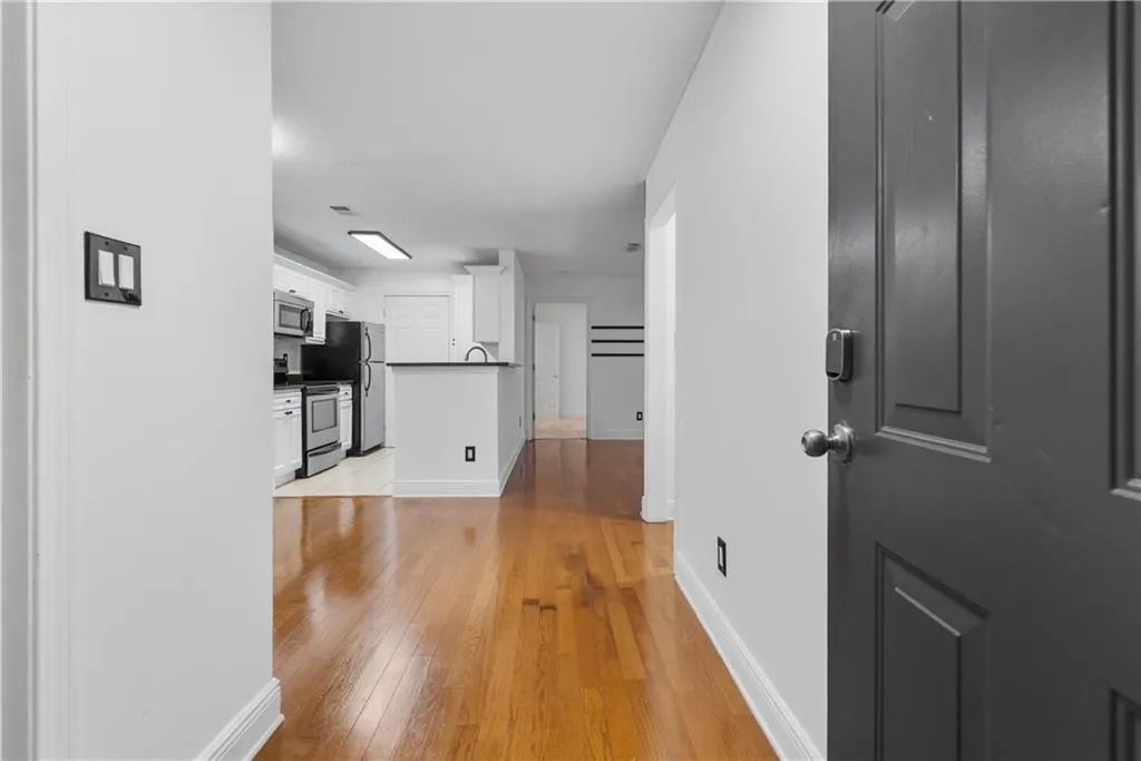 Hallway with light wood-style floors, visible vents, and baseboards