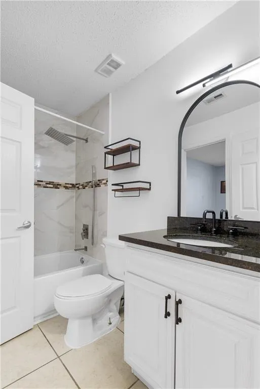 Bathroom with tile patterned flooring, visible vents, and a textured ceiling