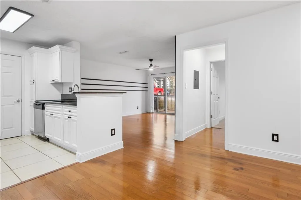 Kitchen with white cabinetry, a ceiling fan, dishwasher, light wood finished floors, and dark countertops