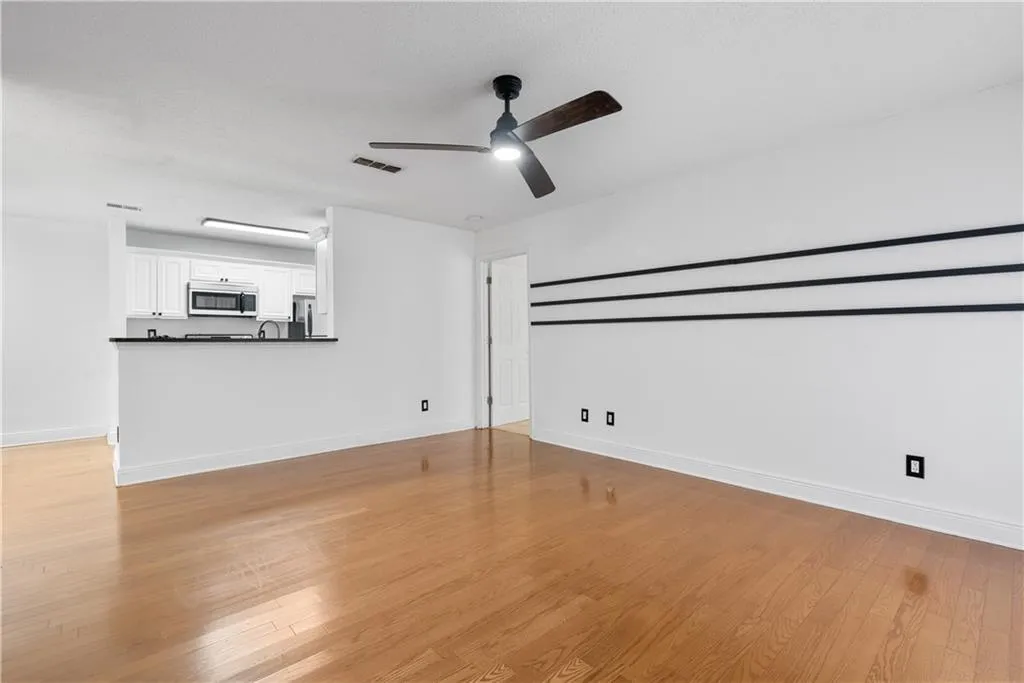 Unfurnished living room featuring light wood-style floors, visible vents, ceiling fan, and baseboards