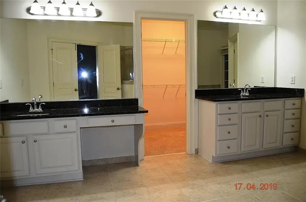 Full bathroom with vanity, a spacious closet, and two sinks
