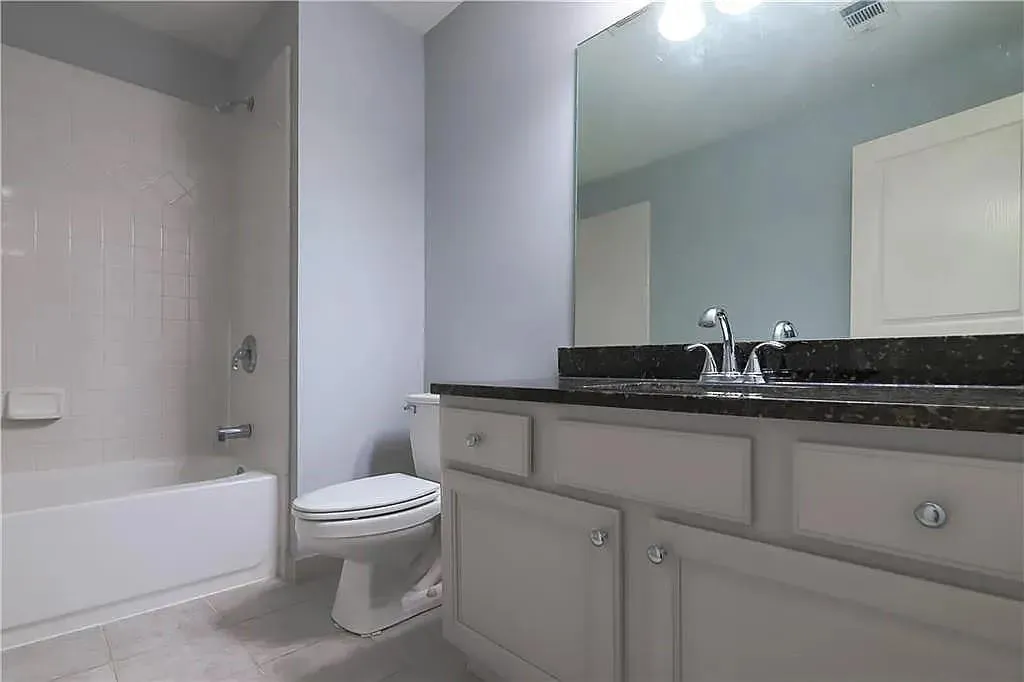 Bathroom featuring vanity, tub / shower combination, and light tile patterned flooring