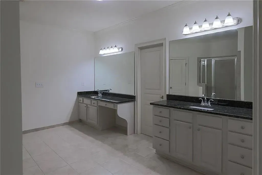Bathroom featuring two sinks, vanity, a shower stall, and light tile patterned flooring