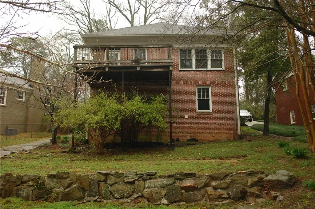 Back of house featuring brick siding and a deck