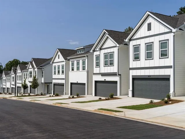 View of property featuring an attached garage, board and batten siding, a residential view, and concrete driveway