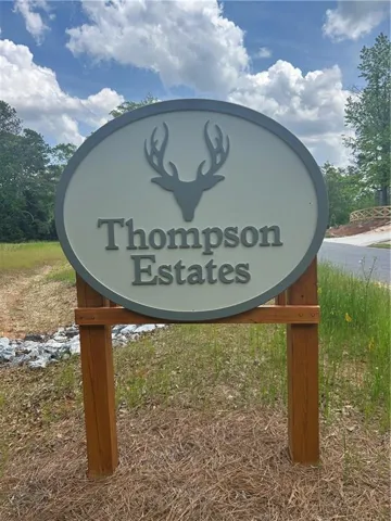 Oval-shaped signage featuring a deer emblem, gray lettering, and a wood-tone post
