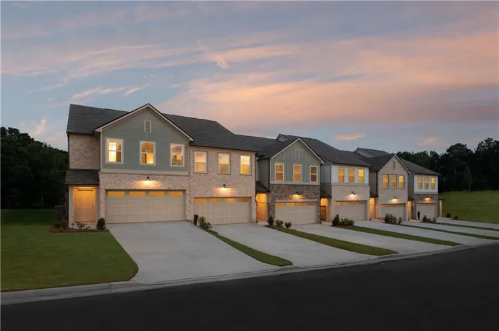 Contemporary townhome-style residences featuring brick and siding exteriors, attached garages, and individual driveways