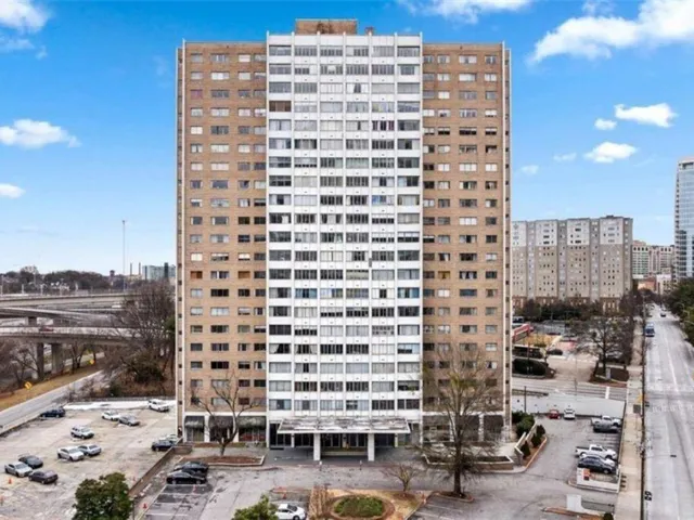 Tall high-rise building with a two-tone facade, featuring multiple window banks and a prominent ground-level entrance