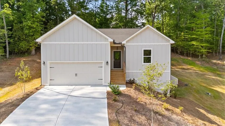 Modern ranch home featuring a clean-lined exterior with vertical board-and-batten siding, a prominent two-car garage with paneled doors, and a welcoming covered entry