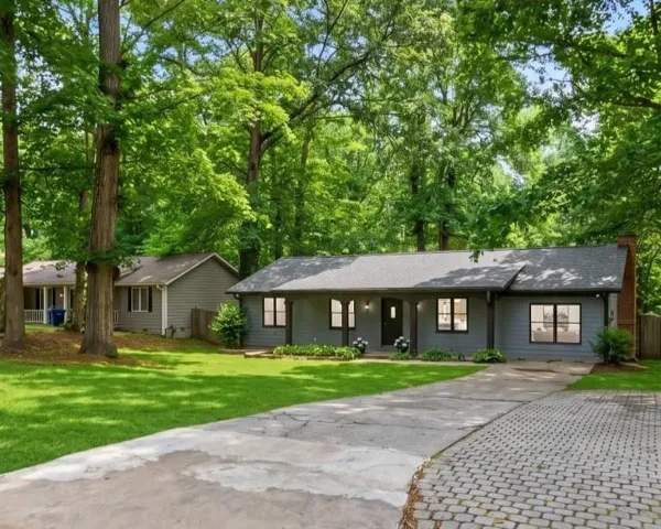 Ranch-style residence featuring a gray exterior, dark-trimmed windows, and a prominent brick chimney