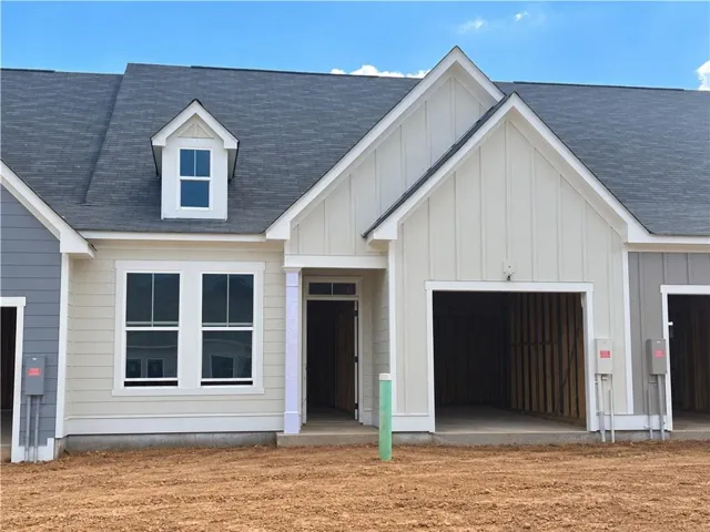 Exterior featuring a dark shingle roof, light-colored siding, a prominent dormer, a front entry, and an open garage