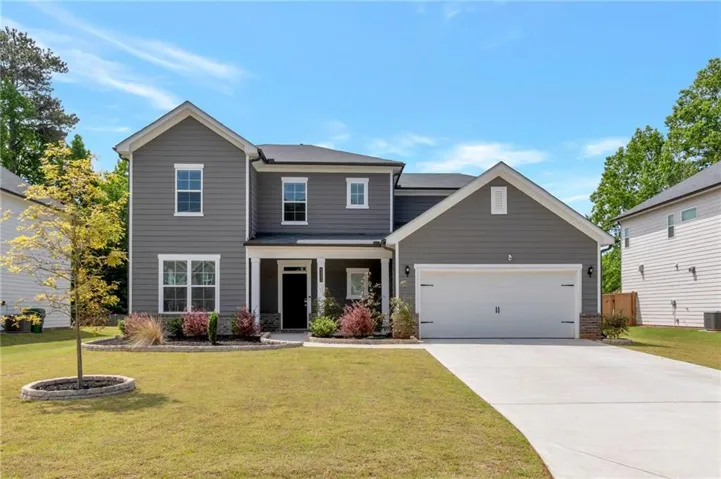 Modern two-story residence featuring grey siding, a covered front porch, and an attached two-car garage