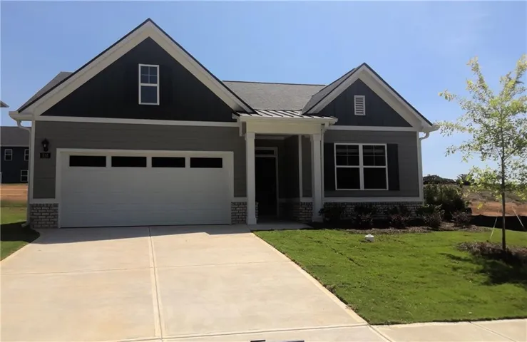 Gray siding with contrasting dark gables, a two-car garage with transom windows, a covered entry with columns, and a concrete driveway