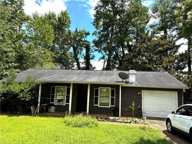 Single-story residence featuring a covered front porch, attached garage with white paneled door, and a dark siding exterior
