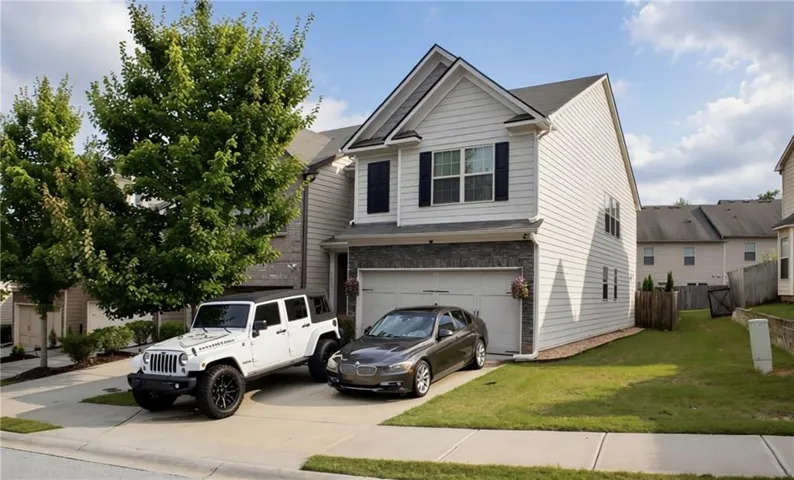 Two-story residence featuring white siding, a two-car garage, and a concrete driveway