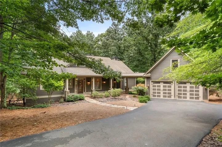 Exterior featuring horizontal siding, a covered entry, a stone-finish pathway, a paved driveway, and an attached two-car garage