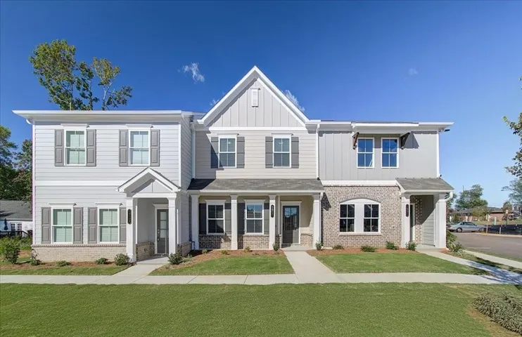 Contemporary townhome architecture featuring mixed materials, shuttered windows, and a covered entry