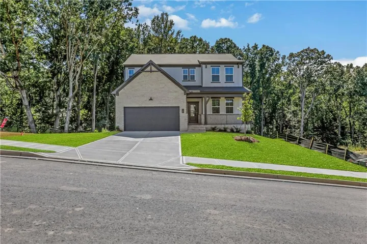 Two-story exterior with a mixed material facade, covered front porch, attached garage, and a concrete driveway