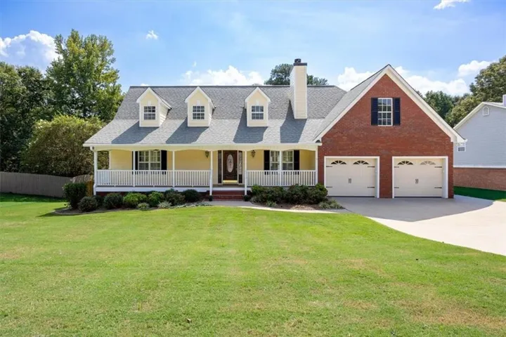 Brick and siding exterior with a covered front porch, multiple dormer windows, and a two-car garage