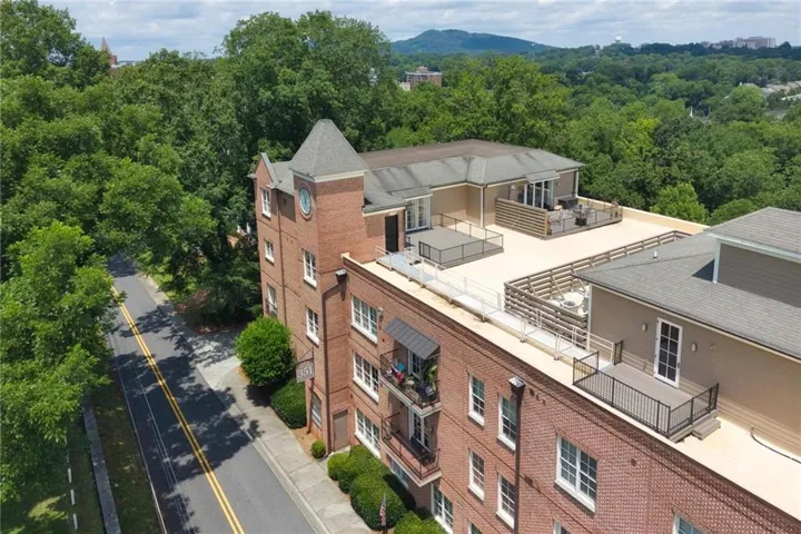 Multi-story brick building featuring a prominent clock tower and multiple private roof terraces