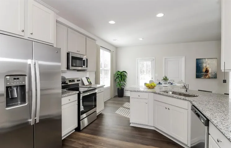 Kitchen featuring stainless steel appliances, light stone counters, dark wood-style flooring, recessed lighting, and white cabinetry