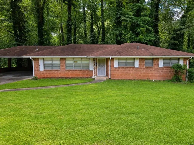 Brick exterior residence featuring a front lawn and a carport