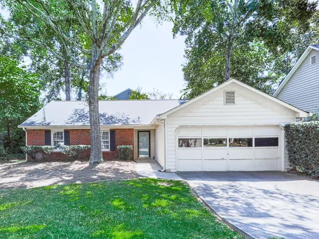 Brick and siding exterior with a white garage door, black front door, and a concrete driveway