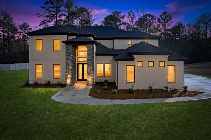 Contemporary exterior with white brick, a prominent stone-clad entry, dark roof, and multiple windows