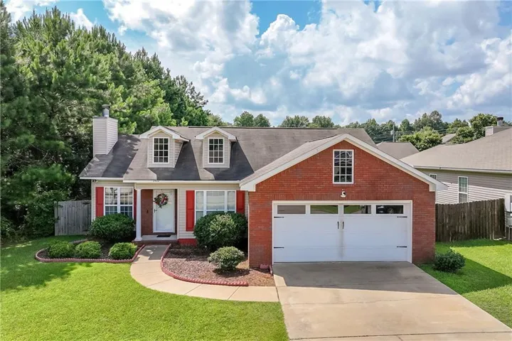 Brick and siding exterior featuring a two-car garage with white doors, a concrete driveway, and a front walkway