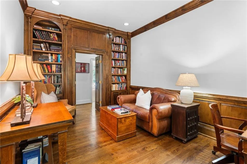 Study to the right of the entry has wood paneling and floor to ceiling bookcases.