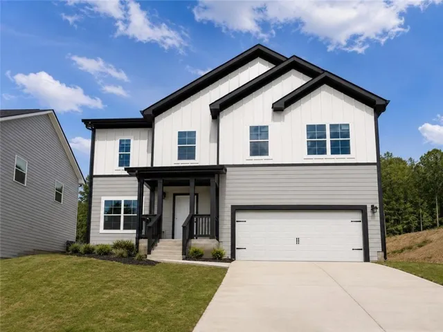 Two-story residence featuring a covered front entry, attached garage, concrete driveway, and a combination of vertical and horizontal siding