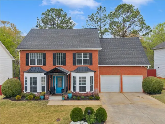 Two-story brick exterior featuring a multi-gable roofline and black window shutters