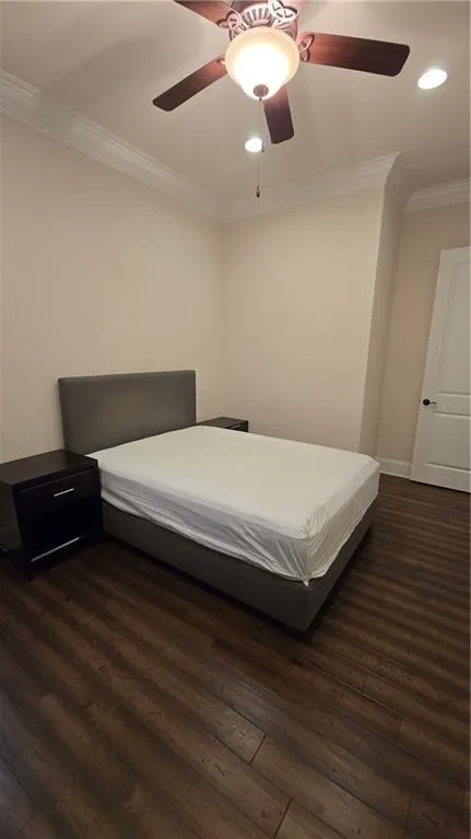 Bedroom with ceiling fan, baseboards, dark wood finished floors, and crown molding