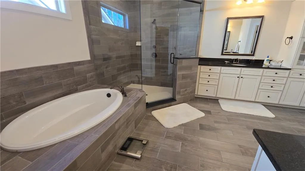 Full bathroom featuring a bath, a shower stall, and vanity