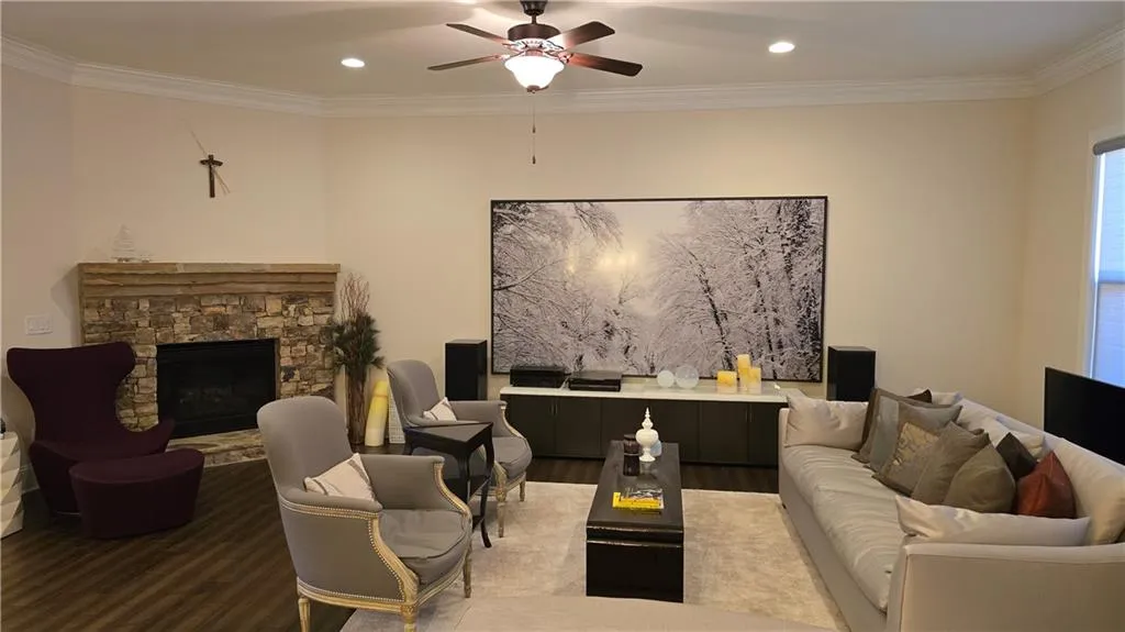 Living room with a fireplace, crown molding, wood finished floors, and ceiling fan