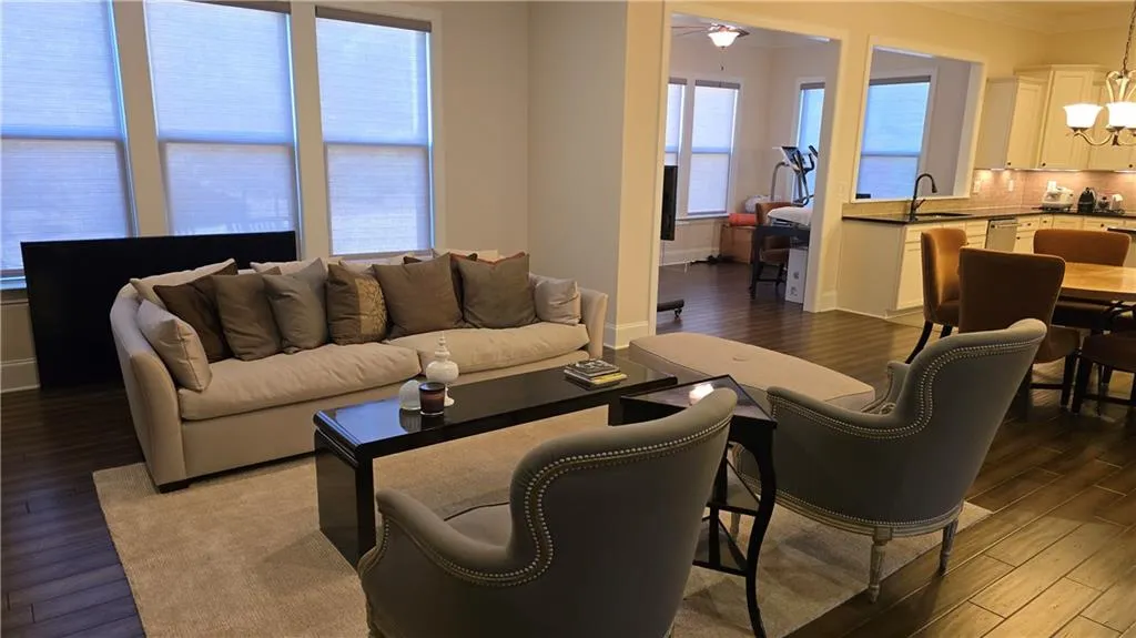 Living room featuring dark wood-type flooring, ceiling fan with notable chandelier, baseboards, and ornamental molding
