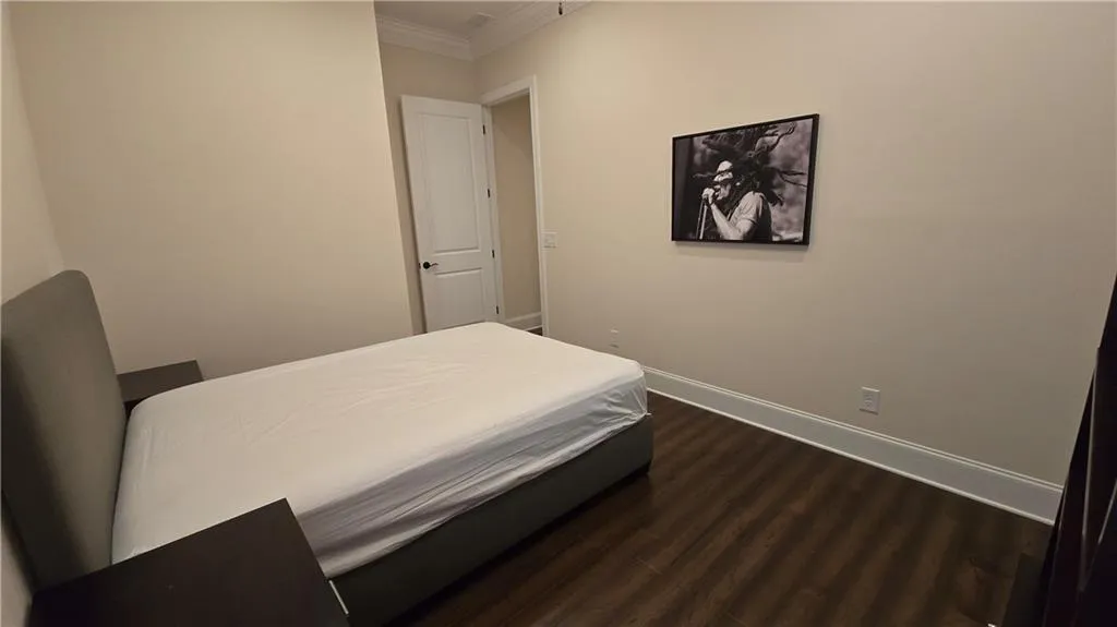 Bedroom with dark wood-type flooring, baseboards, and ornamental molding