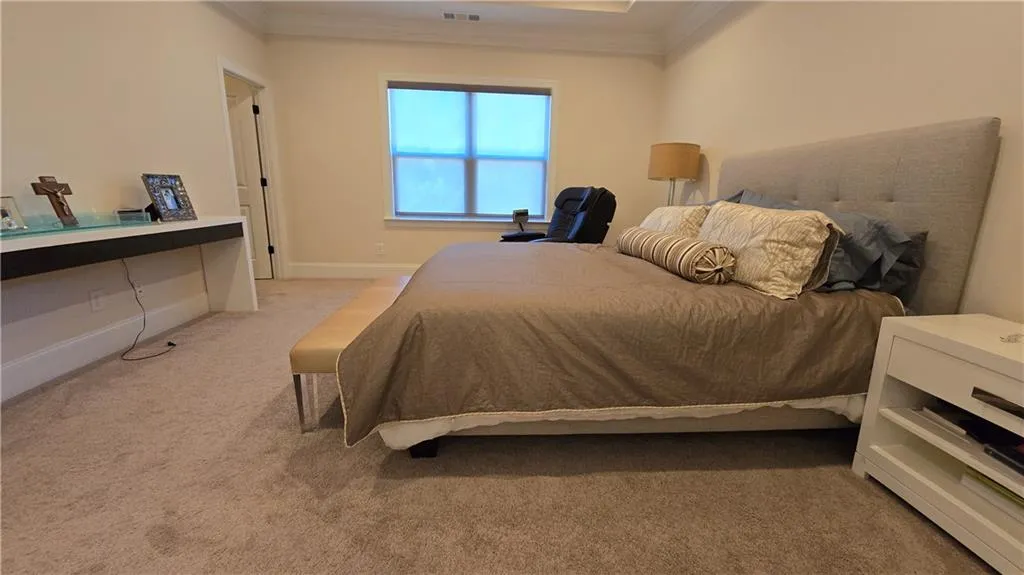 Bedroom featuring visible vents, light colored carpet, baseboards, and ornamental molding