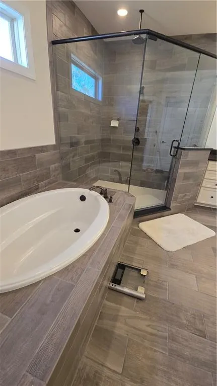 Bathroom with a wealth of natural light, a garden tub, and a stall shower